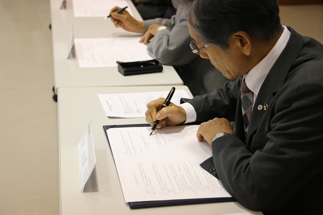 協定書に署名する松本市長 協定書に署名する松本市長