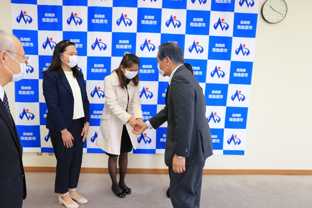 帰国する3人と松本市長が握手を交わす様子