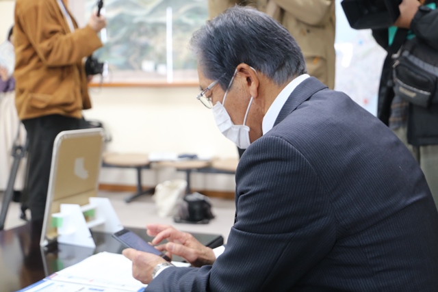 松本市長がミナコインアプリをダウンロード操作している様子
