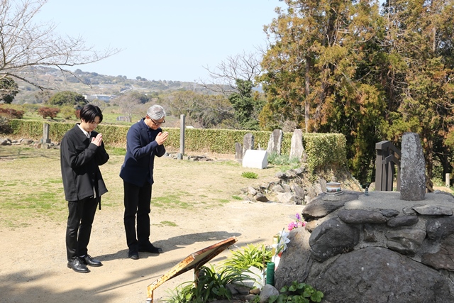 天草四郎の墓に手を合わせる小池さん（左）と堤さん（右）