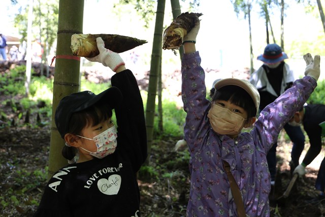 タケノコを手に笑顔を見せる児童