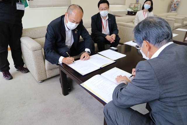 協定書に署名する水野支配人支社長と松本市長