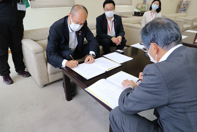 協定書に署名する水野支配人支社長と松本市長 協定書に署名する水野支配人支社長と松本市長